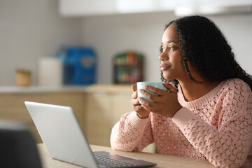 Serious black woman with laptop having a coffee break