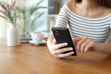 Closeup of a woman hands using mobie phone on wooden table