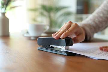 Closeup of a woman hand stapling papers on a table at home