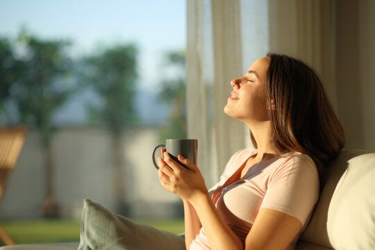 Happy woman holding coffee cup breathing and enjoying aroma