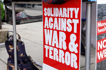 Protest rally with signs promoting unity, peace, and antiwar messages, advocating for justice and...