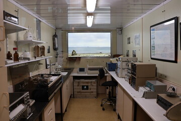 Configuración compacta de laboratorio dentro de un contenedor, idéntica a la utilizada en las expediciones antárticas. El espacio cuenta con un microscopio, equipo científico, una silla y un pequeño © Emotion