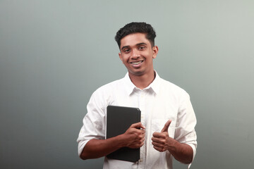 Happy young teenager of Indian origin holding a laptop device in hand