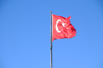 The Turkish Flag waving on the flagpole. The red Turkish Flag with star and crescent waves in the blue sky. October 29, April 23, May 19, August 30, July 15. The flag of the Republic of Türkiye.