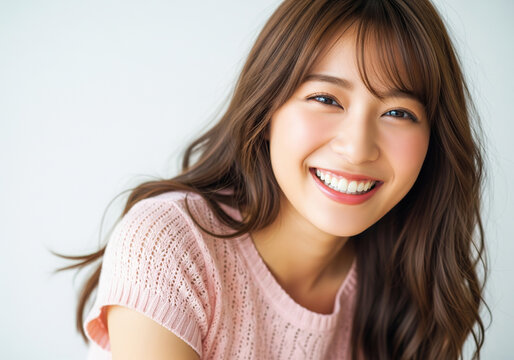 幸せな笑顔のアップショット：シンプルな背景のピンクニットの日本人女性