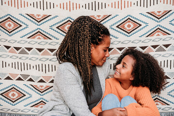 Smiling woman with daughter in front of patterned backdrop