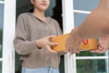 Happy smiling woman receives boxes parcel from courier in front house. Delivery man send deliver...