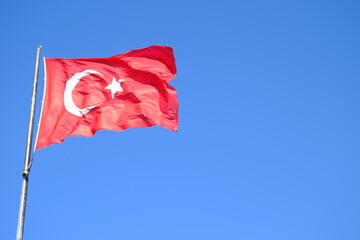 The Turkish Flag waving on the flagpole. The red Turkish Flag with star and crescent waves in the blue sky. October 29, April 23, May 19, August 30, July 15. The flag of the Republic of Türkiye.