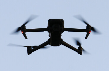 Dron UAV remoto negro de hélices con luces en el aire grabando y vigilando desde el cielo