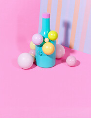 Colorful composition featuring pastel balls and a blue container against a pink and striped background