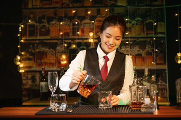 Professional female bartender preparing alcoholic drinks in a bar