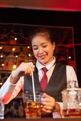 Professional female bartender preparing alcoholic drinks in a bar