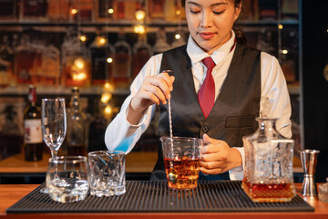 Professional female bartender preparing alcoholic drinks in a bar