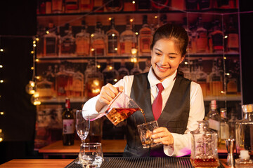 Professional female bartender preparing alcoholic drinks in a bar