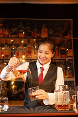 Professional female bartender preparing alcoholic drinks in a bar