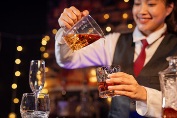 Professional female bartender preparing alcoholic drinks in a bar