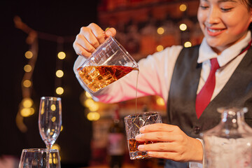 Professional female bartender preparing alcoholic drinks in a bar