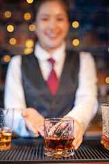 Professional female bartender preparing alcoholic drinks in a bar