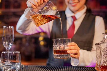 Professional female bartender preparing alcoholic drinks in a bar