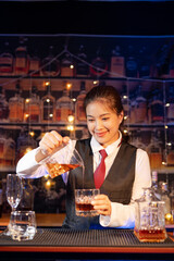 Professional female bartender preparing alcoholic drinks in a bar