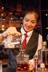 Professional female bartender preparing alcoholic drinks in a bar