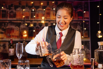 Professional female bartender preparing alcoholic drinks in a bar