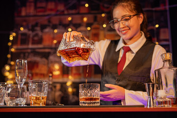 Professional female bartender preparing alcoholic drinks in a bar