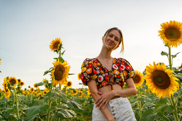 Smiling woman in floral blouse standing in sunflower field