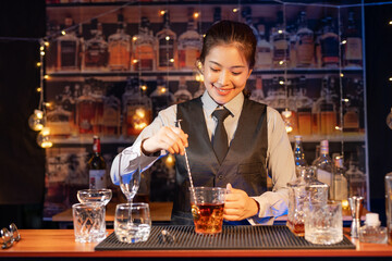 Professional female bartender preparing alcoholic drinks in a bar
