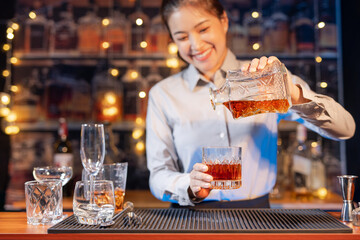Professional female bartender preparing alcoholic drinks in a bar