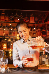 Professional female bartender preparing alcoholic drinks in a bar