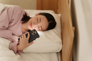 夜ベッドでスマホを使う女性