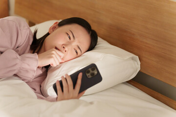 夜ベッドでスマホを使う女性