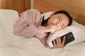 夜ベッドでスマホを使う女性