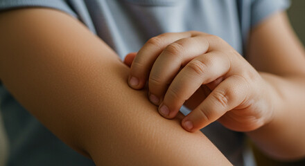 Child scratching arm while wearing a blue shirt indoors  