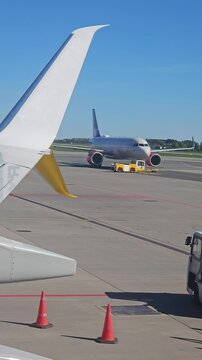 Airplane waiting as pushback tug finishing maneuver on runway. Jet pausing while ground vehicle clearing way for departure. Aircraft standing ready while tow tractor moving aside