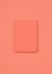 Photo of a blank square poster frame is mounted on a textured orange wall