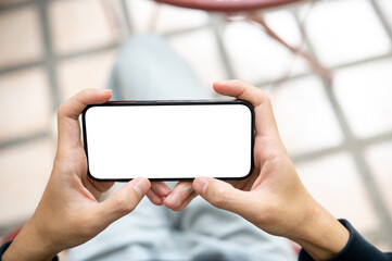 Close up hands holding blank screen smartphone horizontally watching videos or playing game on bench