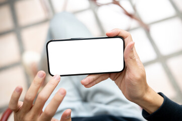 Hand touching white screen smartphone holding horizontally watching videos or playing game on bench.