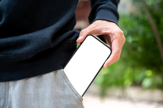 Man hand pulling out white screen smartphone from pants pocket getting a call while standing outdoor