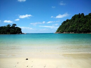 Clear blue tropical sea and empty white sandy beach on a sunny day