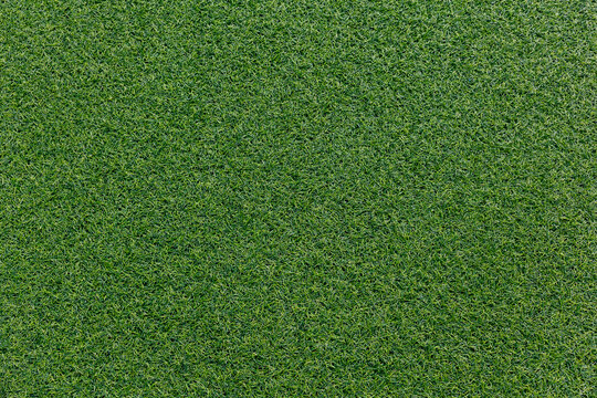 Close-up of artificial turf texture. Vivid green synthetic grass with visible fibers. Sports field or decorative surface background