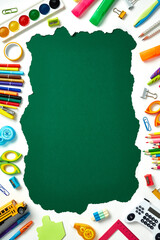 Vibrant school supplies frame a central green copy space. Back to school concept. Flat lay top view.