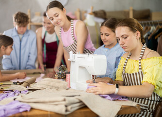 Child watches classmates work on creating clothes, school for young fashion designers and tailors. Optional classes for younger students, professional orientation, and familiarization with profession.