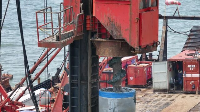 aerial view of the process of installing a giant sea wall by a large drilling machine on the north coast of Java Island