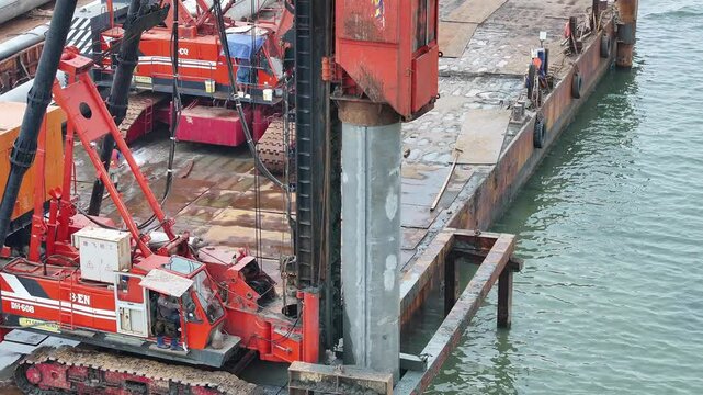 aerial view of the process of installing a giant sea wall by a large drilling machine on the north coast of Java Island