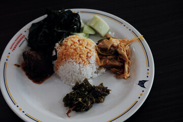 A classic Nasi Padang plate with rice, gulai curry, cassava leaves, young jackfruit gulai,...