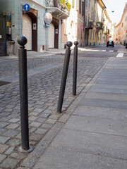 Sturdy round topped bollards protecting pedestrian walkway from cobblestone street, defining urban...