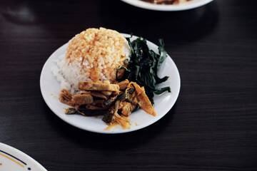 An additional Nasi Padang serving: white rice with gulai sauce, boiled cassava leaves, and young...