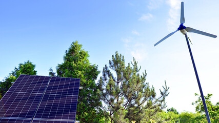 Solar panels with wind turbine on blue sky. Concept of clean energy. Green technology for future. 
